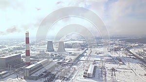 Industrial factory and smoking chimney in winter city drone view. Smoke emission from industrial pipes on power plant