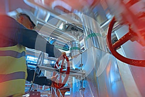 Industrial factory worker turning red wheel of valve