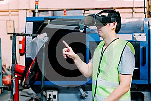 Industrial factory worker wearing VR goggle touching in virtual reality world inside factory