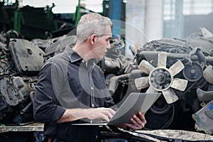 Industrial foreman worker using a laptop computer at manufacturing plant factory industry, senior male engineer with many engine