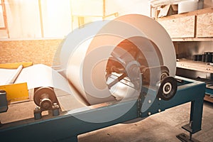 Industrial galvanized steel roll coil for metal sheet forming machine in metalwork factory workshop, sunlight