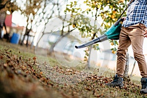 industrial gardner using electric leaf blower in the garden