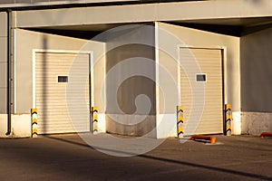 Industrial gray unit facade of storehouse with closed white metal gates doors at sunset