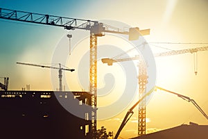 Industrial heavy duty construction site with tower cranes and building silhouettes