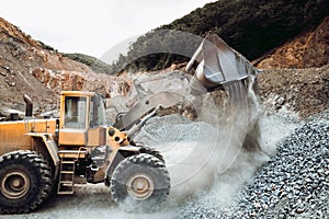 Industrial heavy duty wheel loader moving gravel on construction site.