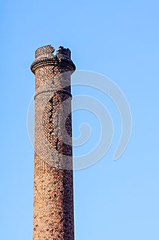 Industrial heritage, dangerously crumbled and cracked red brick chimney photo