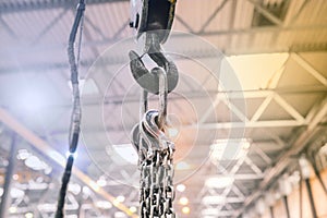 Industrial hook on a metal chain in a factory. Crane in the workshop for lifting heavy objects. Equipment for work at