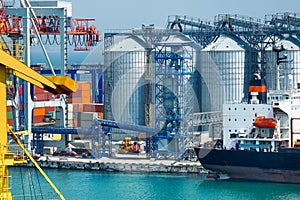 Industrial infrastructure of seaport, sea, cranes and dry cargo ship, grain silo, bulk carrier vessel and grain storage elevators