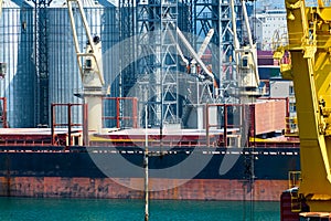 Industrial infrastructure of seaport, sea, cranes and dry cargo ship, grain silo, bulk carrier vessel and grain storage elevators