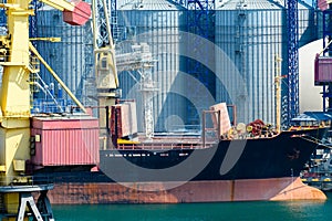 Industrial infrastructure of seaport, sea, cranes and dry cargo ship, grain silo, bulk carrier vessel and grain storage elevators