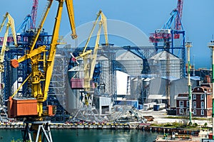 Industrial infrastructure of seaport, sea, cranes and dry cargo ship, grain silo, bulk carrier vessel and grain storage elevators