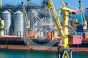 Industrial infrastructure of seaport, sea, cranes and dry cargo ship, grain silo, bulk carrier vessel and grain storage elevators