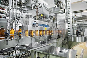 Industrial interior of natural juice plant production. Conveyor belt, filled bottles on beverage factory, industry photo