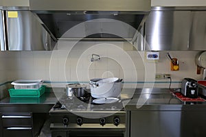 industrial kitchen with stainless steel cookers and suction hood