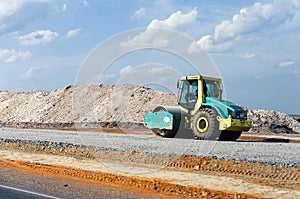 Industrial landscape with big roller compact gravel in speedway. Construction of a layers road amidst backdrop of gravel, crushed