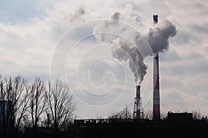 Industrial Landscape, Krakow, Poland: White-red high pipes of the plant with smoke or steam coming out on background of gray-white