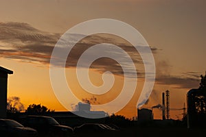 Industrial landscape - orange sunset over a working factory, smoke from the pipes makes purple clouds