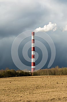 Industrial landscape. Smoke white and red pipe. Beautiful sky and dray grass at sunset