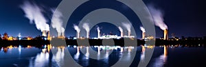 Industrial landscape with smoking chimneys and reflection in water at night