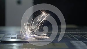 Industrial laser cutter with sparks. The programmed robot head cuts with the aid of a huge sheet of metal temperature