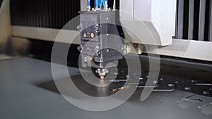 Industrial laser cutter with sparks. The programmed robot head cuts with the aid of a huge sheet of metal temperature