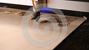 Industrial laser is cutting a pattern on a plywood sheet and moving slowly