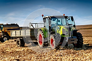Industrial machinery in agriculture fields - Tractor, Combine and farmers working the fields
