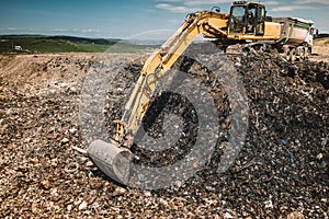 Industrial machinery excavating garbage. Close up of heavy duty excavator using scoop and working