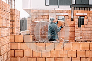 Industrial male bricklayer installing bricks on construction site.