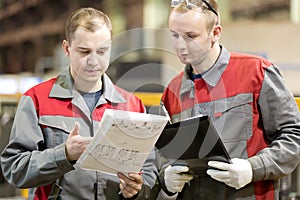 Industrial manufacturing workers reading engineering drawing