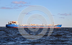 Industrial merchant seagoing vessel sails on small waves in  pre-storm weather.  ship with  cargo goes to  point of delivery of