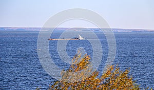 Industrial merchant seagoing vessel sails on small waves in  pre-storm weather.  ship with  cargo goes to  point of delivery of