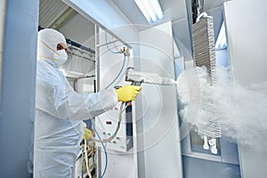 Industrial metal coating. Man in protective suit, wearing a gas