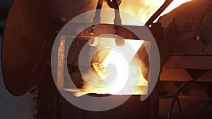 Industrial molten steel pour from furnace with intense heat, sparks in metalwork foundry, metallurgy process. Workers