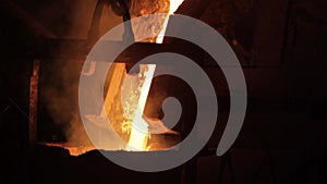 Industrial molten steel pouring in foundry. Metal casting process in manufacturing plant, fiery orange glow from furnace