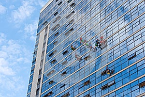 Industrial mountaineering, group of workers cleaning windows service on high rise building. work on the heights