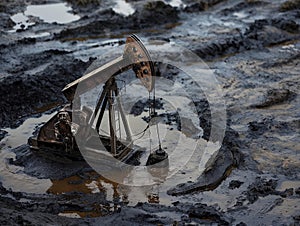 Industrial Oil Pump Jack Mining Crude in a Muddy Field