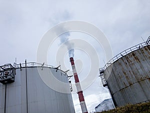 Industrial oil refinery storage tanks with smokestack pollution