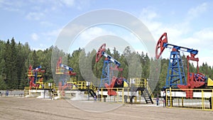 Industrial oil well pump jacks pumping crude oil for fossil fuel energy with drilling rigs in oil field. Nodding donkey