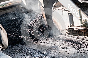 Industrial pavement machine laying fresh asphalt on highway construction site