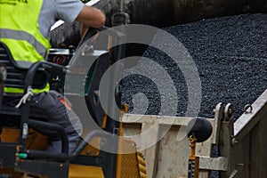 Industrial pavement machine laying fresh asphalt on road construction.