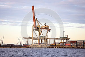Industrial photo of unloading cranes and equipment near river docks