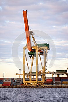 Industrial photo of unloading cranes and equipment near river docks