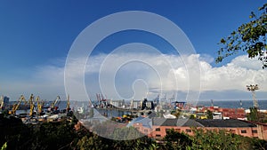 Industrial port landscape with cargo cranes and grain elevators under cloudscape