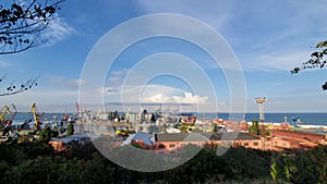 Industrial port landscape with red warehouse buildings and grain elevators under cloudscape