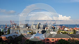 Industrial port landscape with red warehouse buildings and grain elevators under cloudscape