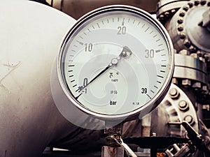 Industrial pressure gauge  in bar on a line of large metal pipes