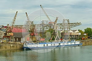 Industrial River Scene With Blue Cargo Barge and Cranes on an Overcast Day