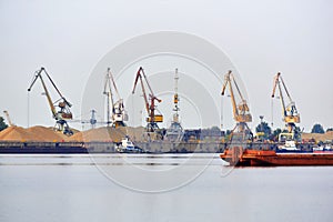 Industrial river waterscape with cargo terminal and mooring barges and tugboats