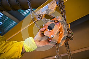 Industrial rope access inspector worker rigger hand commencing safety daily inspection check on lifting hoist chain block